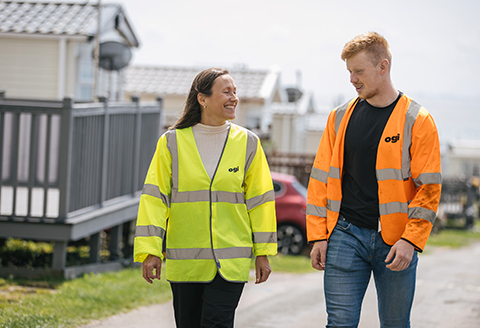 Two engineers in high vis jackets walking through a leisure park.