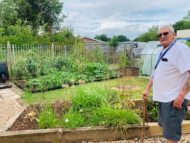 Person stood next to a community garden.