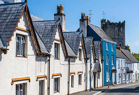 A row of rooftops can be seen leading to a church bell tower. A bright blue sky completes the frame.