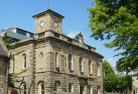 A town hall building cropped to focus on the crest and clock tower.